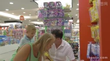 年轻的父母和儿子一起在超市买玩具，他们看着盒子里的游戏和选择